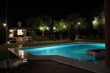 vista nocturna jardín y piscina